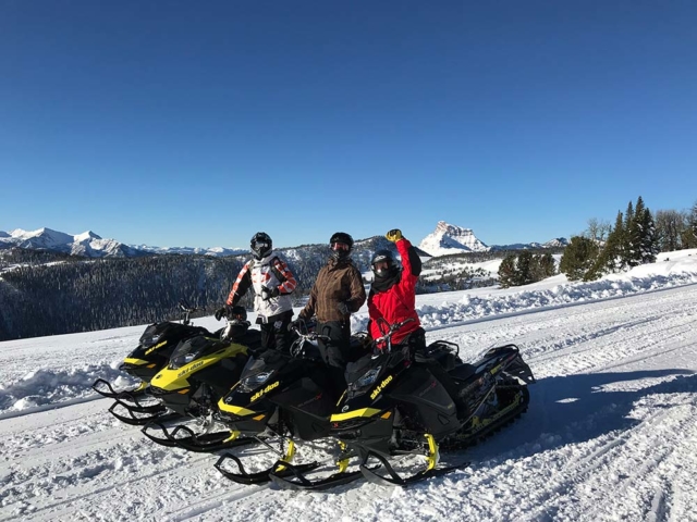 group of three riders snowmobiling in montana