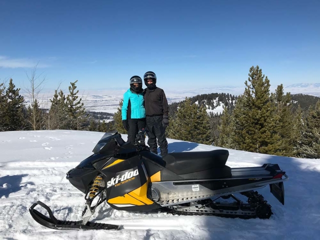 trail riders snowmobiling in montana in mountains