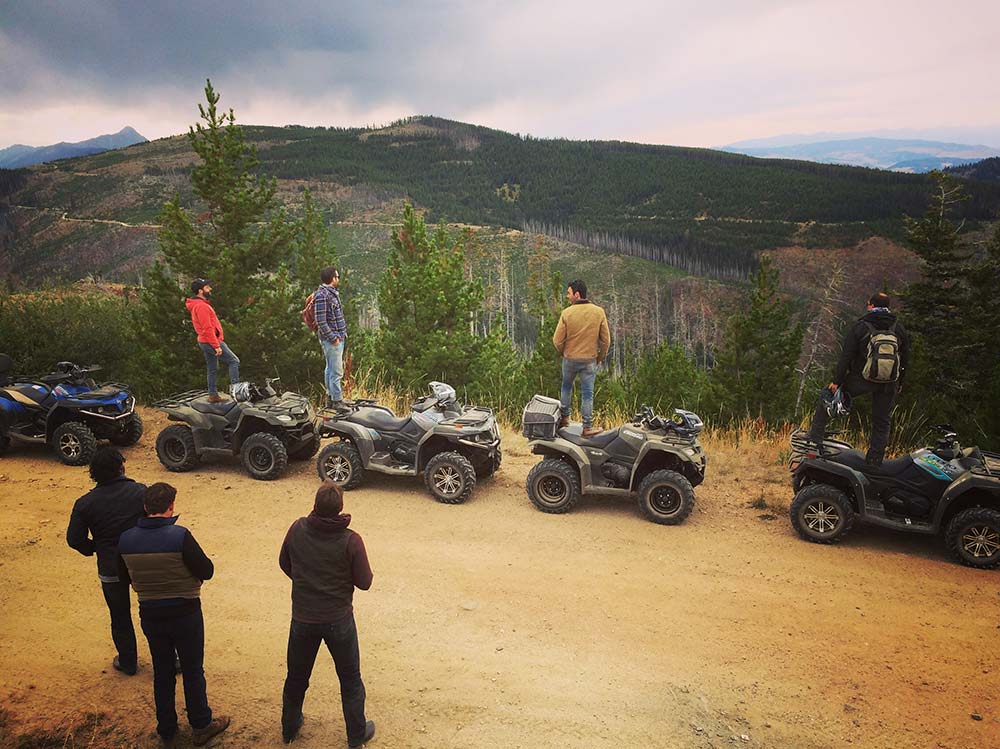 friends standing on their atvs on montana trail